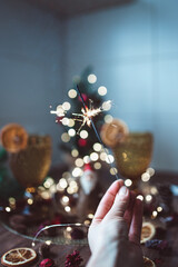 Woman's hand holding sparkler on the background of the Christmas tree