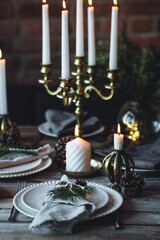 Rustic Scandinavian style zero waste eco-friendly dinner table decor for Christmas or new year family celebration. Wooden table, natural elements like pine cones, fir tree branches, candles