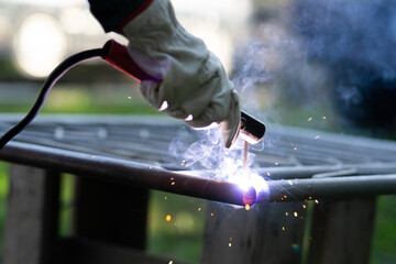 Close up of a welder welding metal frame outdoors
