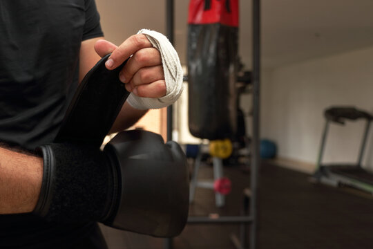 Boxer in a gym wrapping his hands with white bandages, adjusting his black gloves before a training session the preparation ensures safety and protection for his hands during intense punching drills