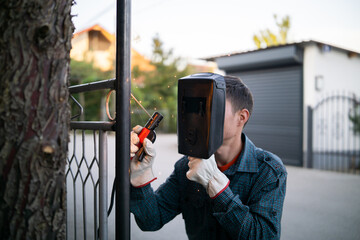 Close up of a welder welding metal fence outdoor