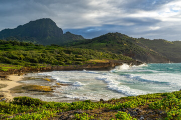 Dramatic view of Haupu Mountain and Pakamoi Bay at the far end of the Maha'ulepu heritage trail with the hills covered with Ironwood pin and Naupaka bush, Kauai, Hawai'i