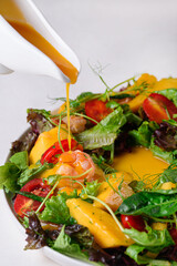 salad. shrimps, pineapples, tomatoes, lettuce leaves, micro-greens on a white background