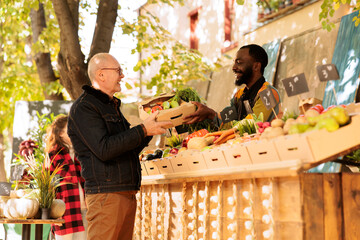 Happy elderly male person getting box of locally grown fruits and veggies at farmers market,...