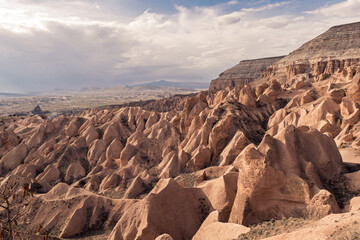 A vast landscape of the unique rock formations in Cappadocia, Turkey, bathed in soft sunlight,...