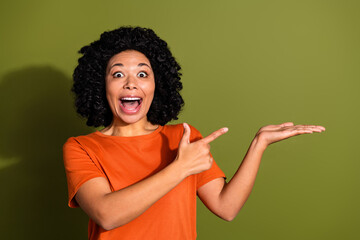 Photo portrait of lovely young lady point hold amazed empty space dressed stylish orange garment isolated on khaki color background