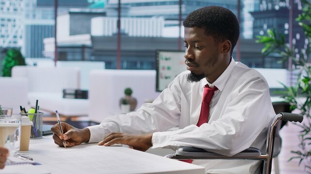 Wheelchair user job seeker fills in application form during interview, discuss with HR team about assistive integration within the company. Disability friendly inclusive adaptive office. Camera A.