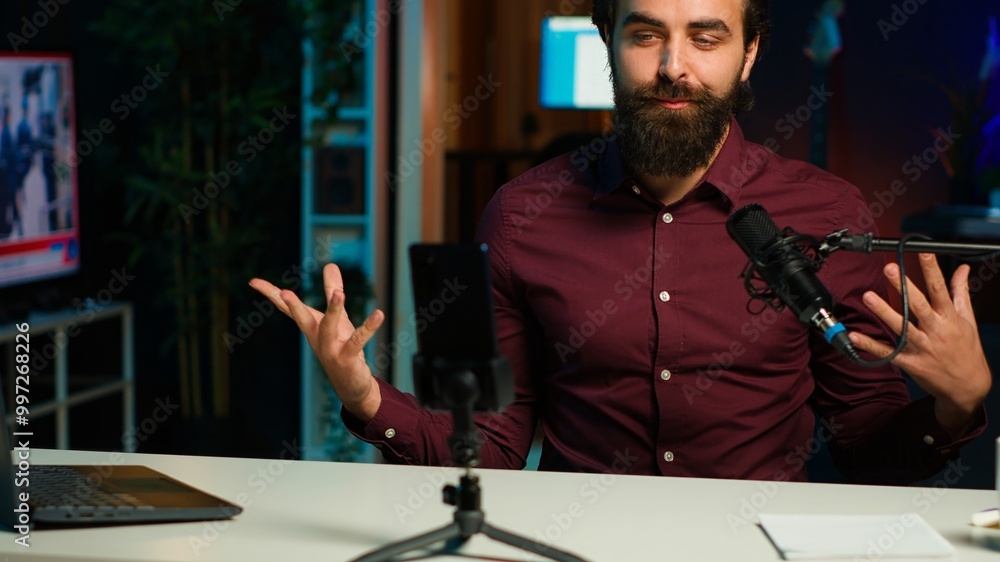 Poster influencer talks in front on smartphone attached to tripod and high quality mic in studio, discussin