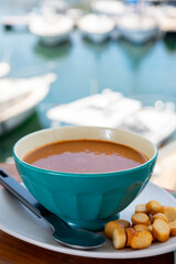 Homemade tasty fish or bisque soup with croutons and view on yacht boats and houses of Port Grimaud, French Riviera, France. Food of Provence