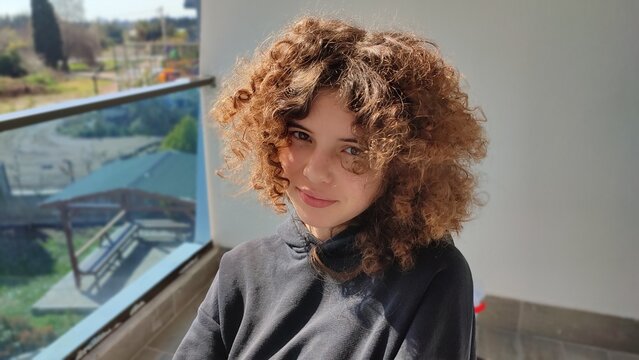 The teenager is in a good mood. Girl's new hairstyle. Cheerful happy child's face and lively emotions. Stare and mistrust