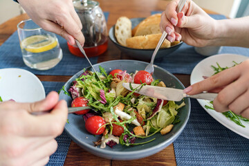 People Sharing a Fresh Salad at a Dining Table With Drinks and Bread in a Casual Setting During a Sunny Day