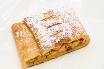 Slice of sweet apple strudel cake on a white plate with white background