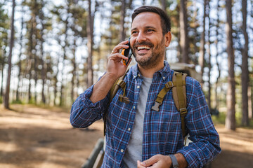 adult man have a phone call on cellphone in front car in the forest