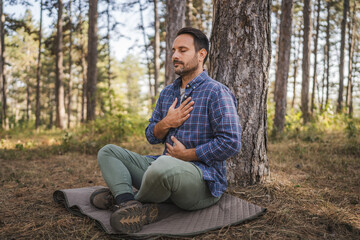 Adult man camper practice meditation and breath exercise in front tree