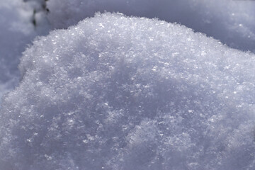 Close-up texture of fresh, clean, sparkling, freshly fallen snow. Fallen snow sparkles in sun. Winter background. Background for design of Christmas themes.