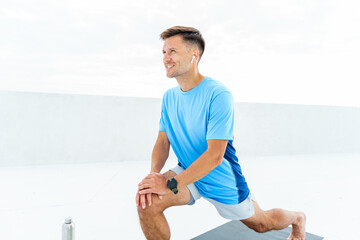 Man Performing a Lunging Stretch on a Yoga Mat in a Bright, Airy Gym During Daytime