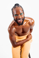 Happy African American shirtless gay model bending while posing over white background. Portrait of...