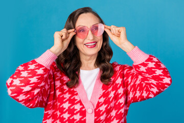 Photo portrait of lovely senior lady look empty space touch sunglass dressed stylish pink print garment isolated on blue color background
