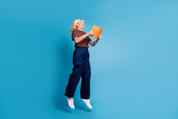 Photo of lovely nice cheerful woman wear trendy brown clothes jump up isolated on blue color background