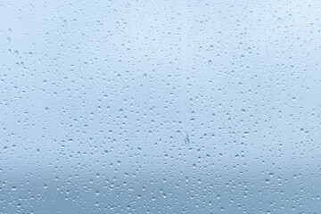 Raindrops forming a delicate pattern on a window pane, blurring the outside view during a cloudy afternoon in early fall