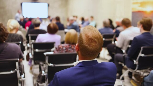 Audience at the modern conference hall listens to panel discussion, people on a congress together listen to speaker on stage at convention, business seminar, amphitheater venue for presentation