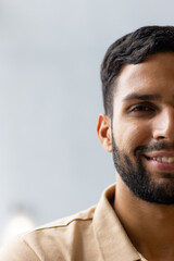 Obraz premium Smiling man with beard wearing beige shirt, looking at camera, close-up portrait, copy space
