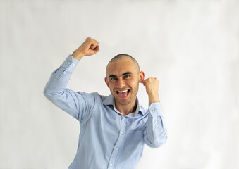 Shaved young man with a big smile rejoicing ecstatically with raised fists