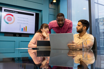 Discussing department budgets, business colleagues using laptop and tablet in office
