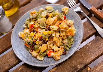 On simple wooden table made of planks there is plate with salad, cutlery, decanter with olive oil....
