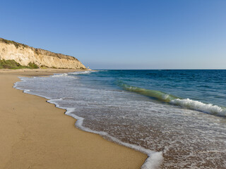 Serene California sandy beach with waves washing up and cliffs in the distance