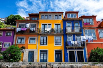 Fototapeta premium View of Porto from the Douro River, with colorful houses stacked on top of one another, traditional balconies, and laundry hanging out to dry, capturing the essence of local life