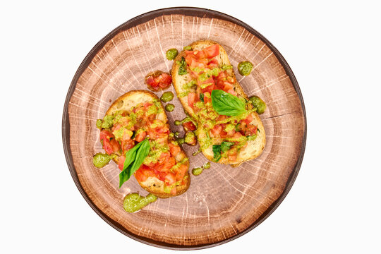 Traditional Italian appetizer,homemade bruscheta with tomatoes and basil served on brown plate, isolated on white background