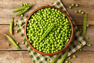 Fresh green peas and pods on wooden table, flat lay