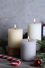 Burning candles, Christmas decor and fir tree branches on wooden table, closeup