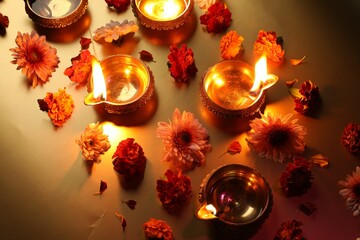 Diwali celebration. Diya lamps and beautiful flowers on golden background, above view