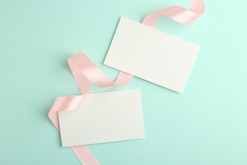 Blank cards and ribbons on turquoise background, flat lay