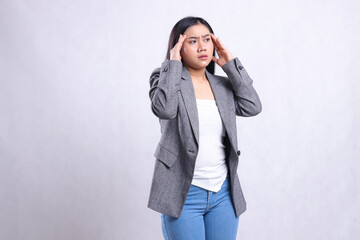 expression of beautiful adult office woman dizzy both hands hold head tilted left wearing gray suit...