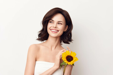 Smiling young woman posing with sunflower on white background