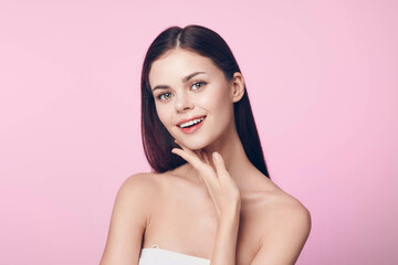 Beautiful young woman with hands on chin posing on pink background