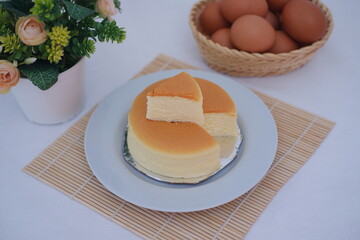 Cheesecake on white plate with flower and eggs in background.