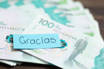 A blue thank you note in spanish on some 100,000 Colombian peso bills. Salary payment.