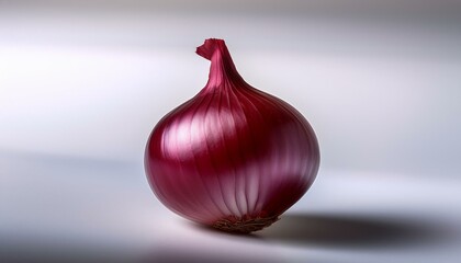  A single red onion with its papery skin intact, centered on a white background, softly lit t