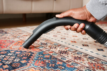 Using a handheld vacuum cleaner to effectively vacuum and clean a colorful area rug thoroughly
