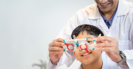 Indian boy doing eye test checking examination with optometrist in optical shop, Optometrist doing...