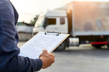 person is holding clipboard with delivery documents while standing near delivery truck. scene captures essence of logistics and transportation, emphasizing importance of organization in delivery