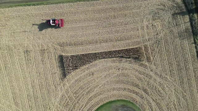 Top view by drone of an agricultural machine harvesting the last part of a cornfield. - Vue de dessus par drone d'une machine agricole r&eacute;coltant la derni&egrave;re partie d'un champ de ma&iuml;s