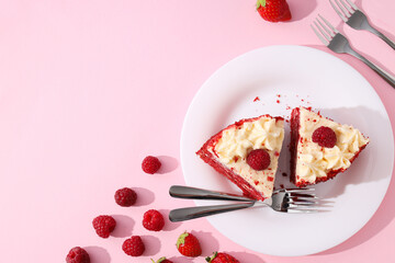 Pieces of red velvet cake on plate and berries on pink background, space for text