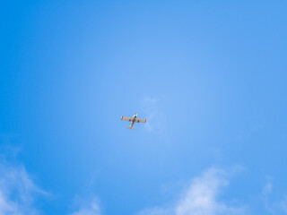 Small ultralight airplane with overhead wing and single propeller flying in sunset sky.