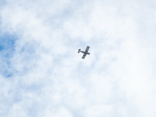 Small ultralight airplane with overhead wing and single propeller flying in sunset sky.