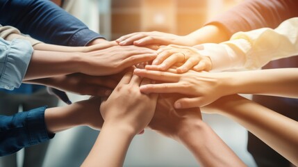 A group of startup company employees stack their hands together in a gesture of unity and teamwork.